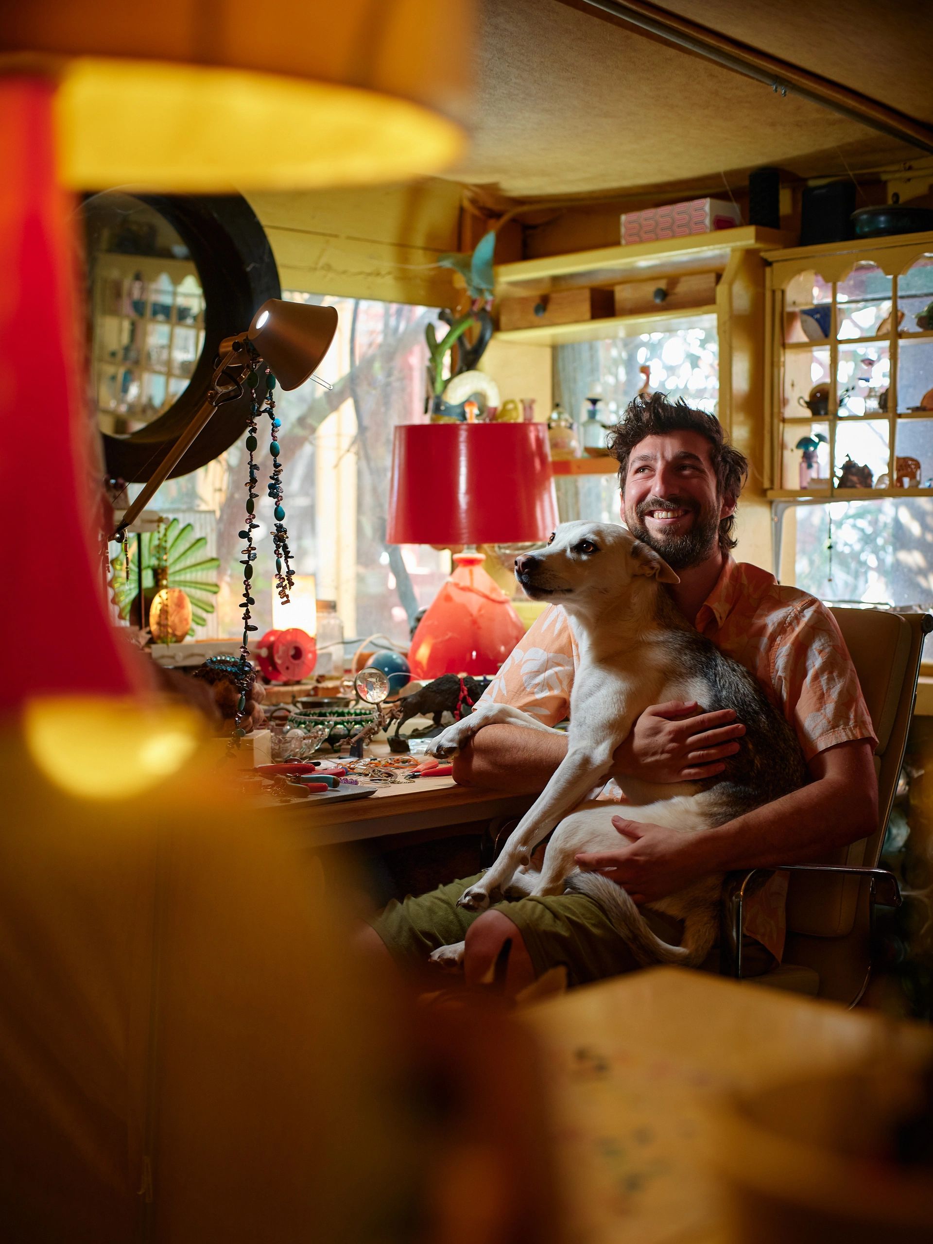 Man happily holding a dog in a cozy, colorful room.