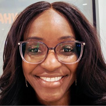 Smiling woman with glasses and long dark hair.