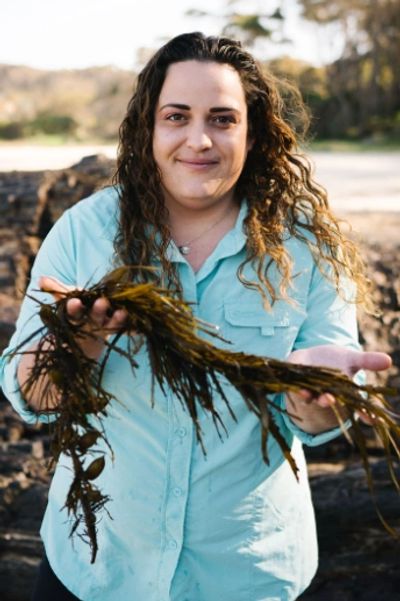 Person holding seaweed outdoors with a smile.