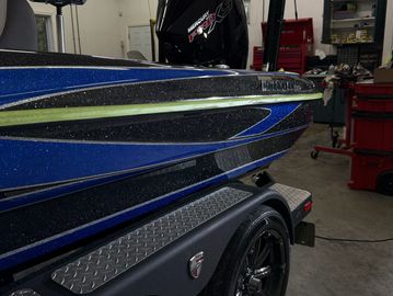 Close-up of a blue and black boat on a trailer indoors.