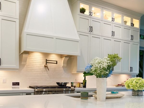 Bright modern kitchen with white cabinetry and fresh flowers on the island.