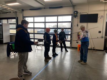 A group of boys learning to fish indoors with fishing rods.