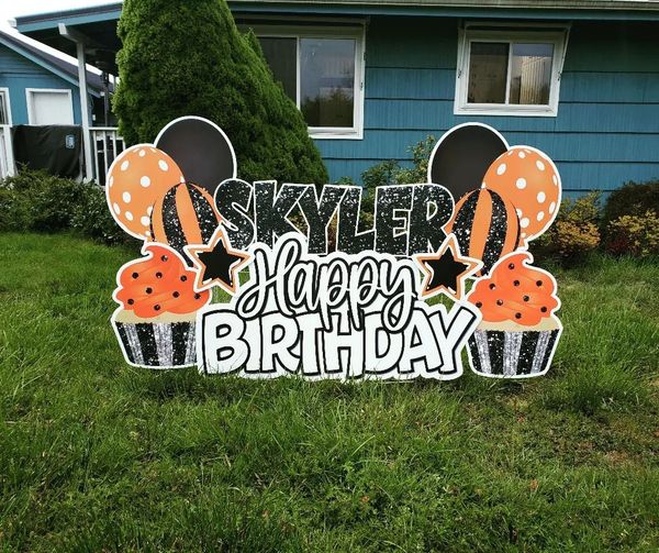 Happy Birthday lawn sign, cupcakes and balloons in orange, black and silver.