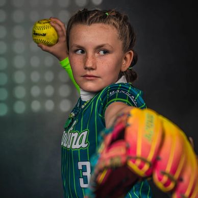 Young softball player preparing to pitch with focused expression.
