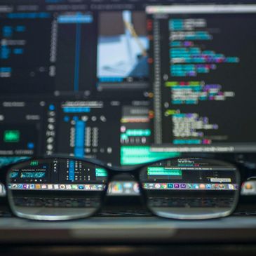 computer code on multiple screens viewed through spectacles on a desk