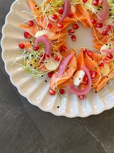 Colorful smoked salmon dish with red onions and pomegranate seeds.