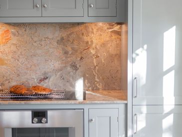 Modern kitchen with marble backsplash and bread on counter.