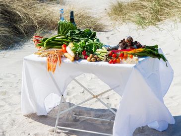 Fresh vegetables and seafood on a table at the beach.