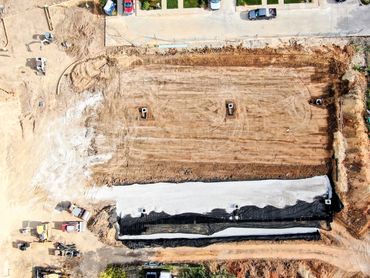 Aerial view of leveled construction site with foundation preparation and construction equipment.