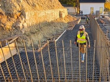 Construction worker walking along rebar. 