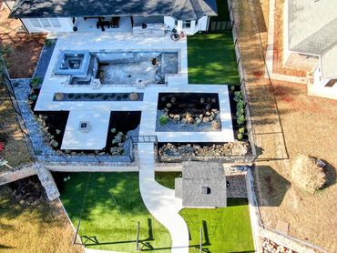 Aerial view of landscaped backyard with unfinished pool, pathways, garden beds, and small shed.