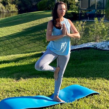 Woman practicing yoga outdoors in a tree pose.