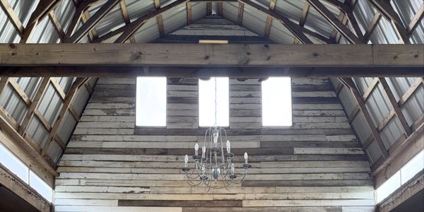 Rustic interior with a chandelier and wooden ceiling beams.