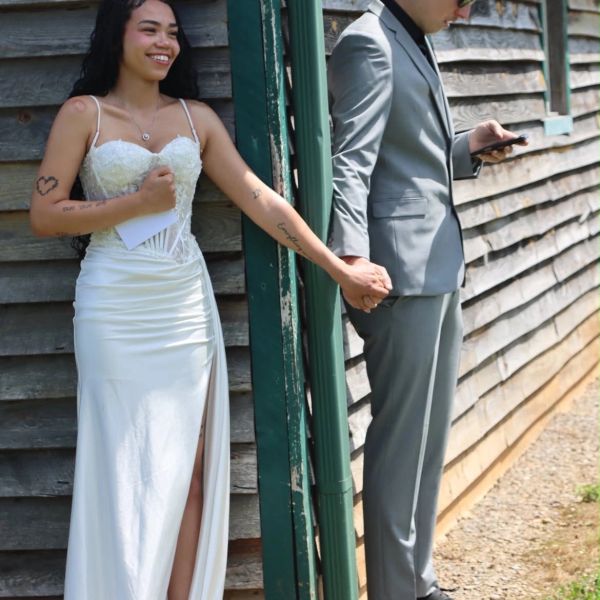 Bride and groom holding hands around a corner.
