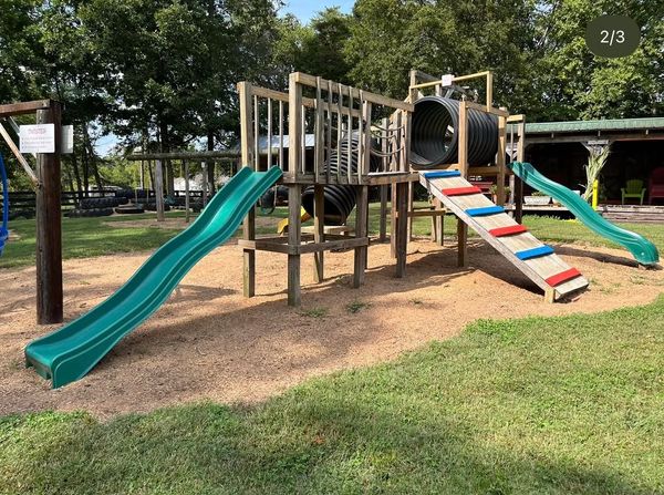 Wooden playground with slides and tunnels outdoors.