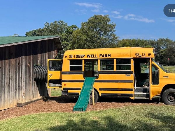 Yellow school bus converted into a play area with slide and tunnel.