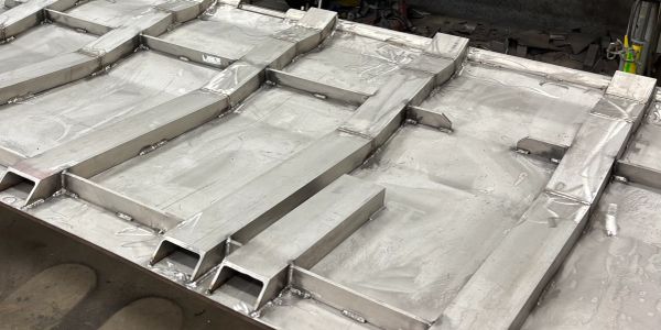 Metal sheet with welded rectangular channels arranged in parallel rows.