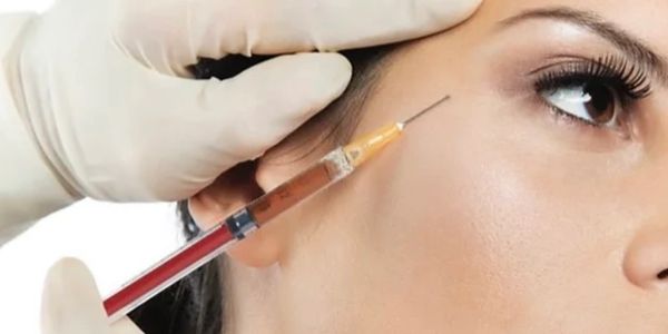 A person receiving an injection on their face near the eye.