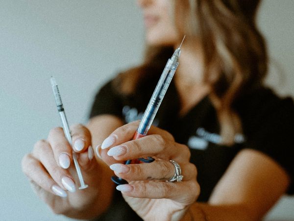 A person holding two syringes, one in each hand.