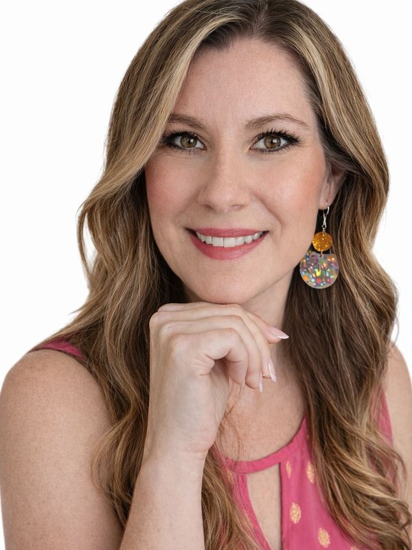 Smiling woman with long wavy hair wearing a pink top and colorful earrings.
short term rental co-host