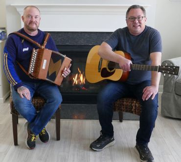 Michael Corbett and Dan O'Connell in front of a fire.