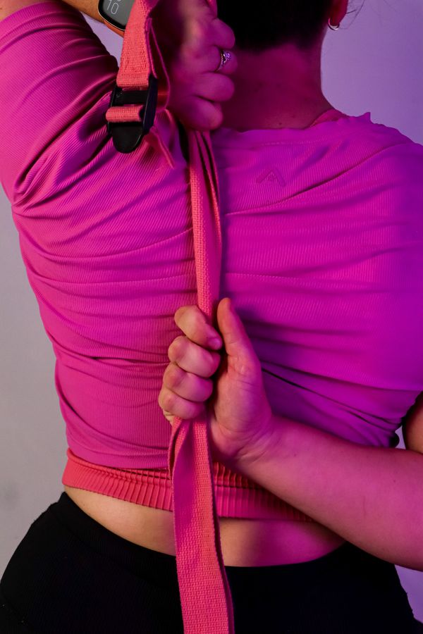 personal trainer holding a stretching strap behind their back. Waist showing under crop top