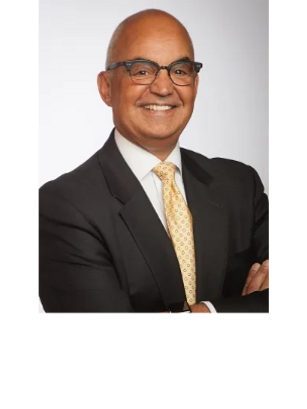 Smiling man in a suit with glasses posing confidently.