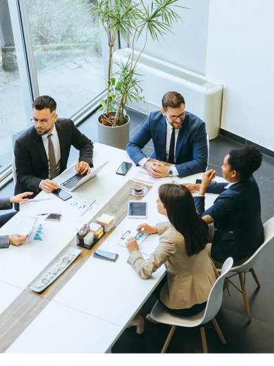 Five professionals engaged in a business meeting around a modern white table.