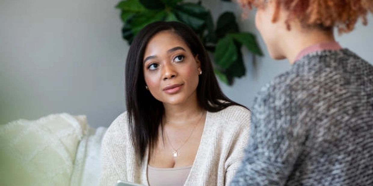 Two women engaged in a thoughtful conversation indoors.