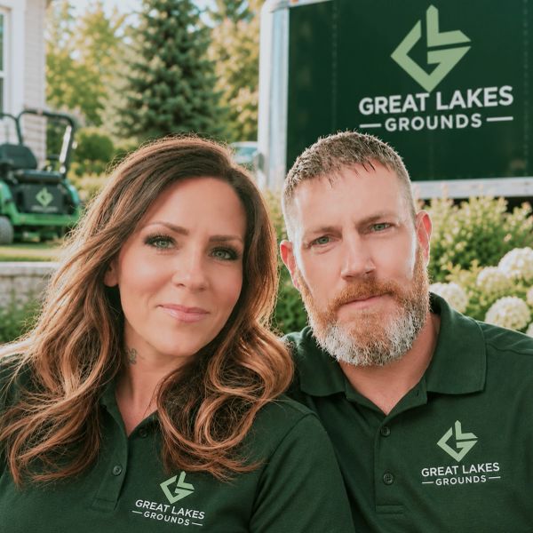 Two people wearing Great Lakes Grounds shirts outdoors.