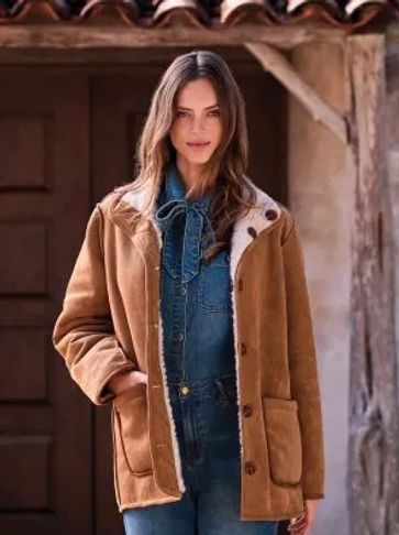 Woman wearing a brown jacket over a denim outfit.