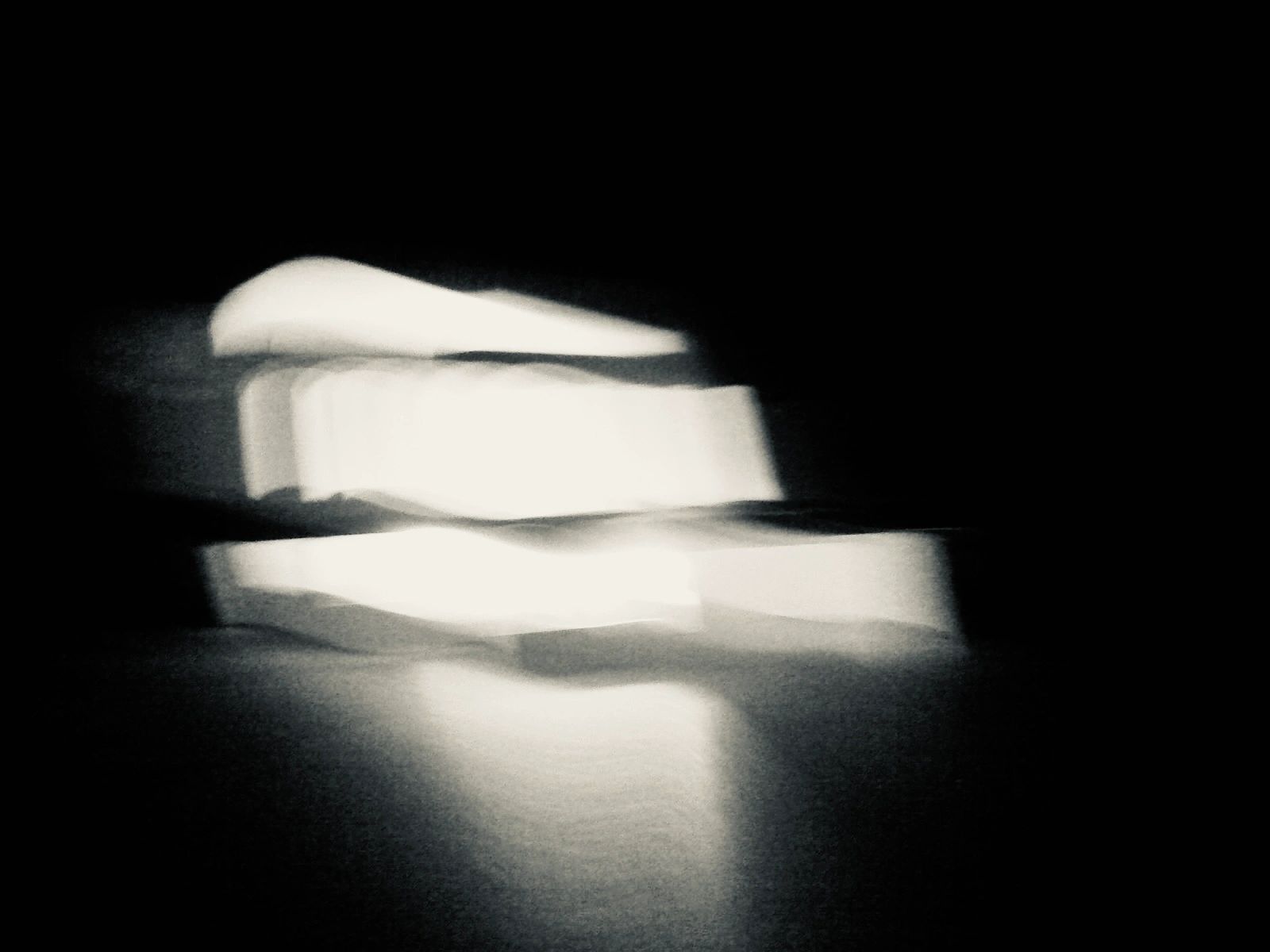Abstract blurry white shapes on black background.