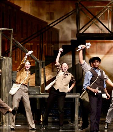 Actors performing energetically on stage in vintage attire.