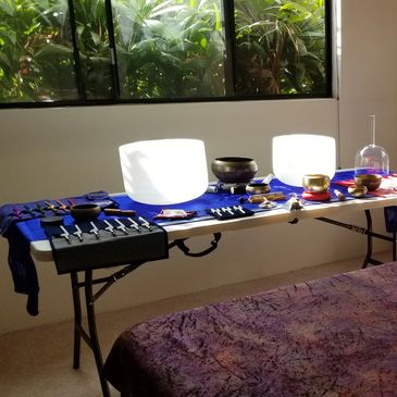 A table with sound healing bowls and tuning forks in a serene room.