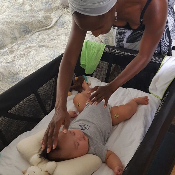 Keema Cooper Giesselmann sharing energy healing with infant in crib