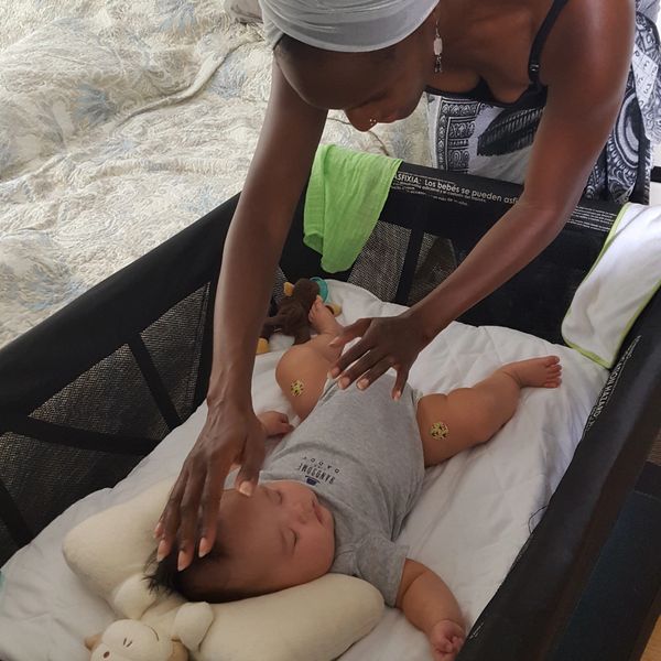 Keema Cooper Giesselmann sharing energy healing with infant in crib