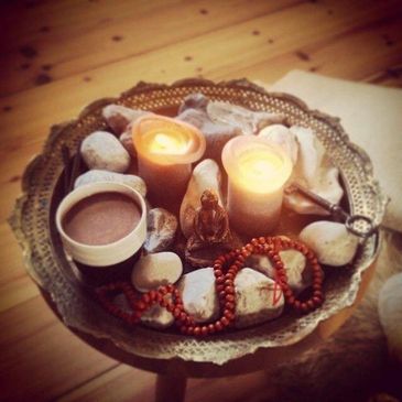 A decorative tray with candles, stones, and a cup of cocoa.