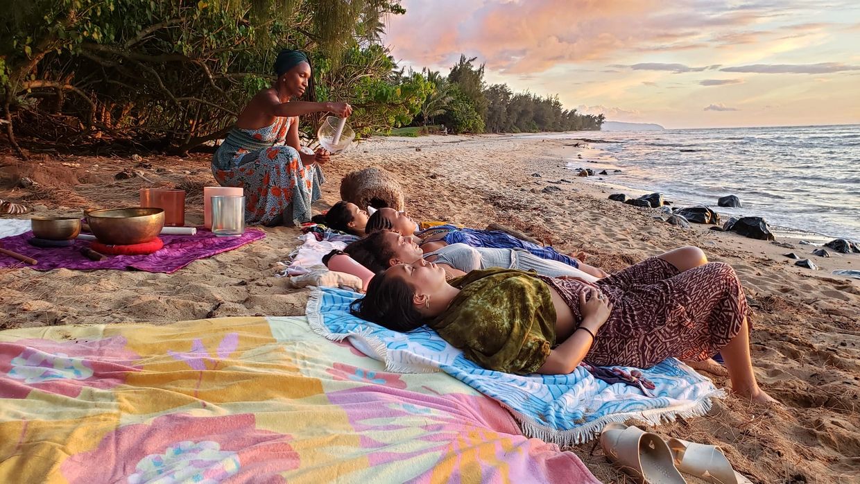 Keema Cooper Giesselmann playing sound bowl for participants on North Shore beach on Oahu Hawaii