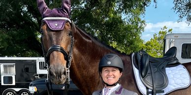 Smiling rider with brown horse and saddle outdoors.