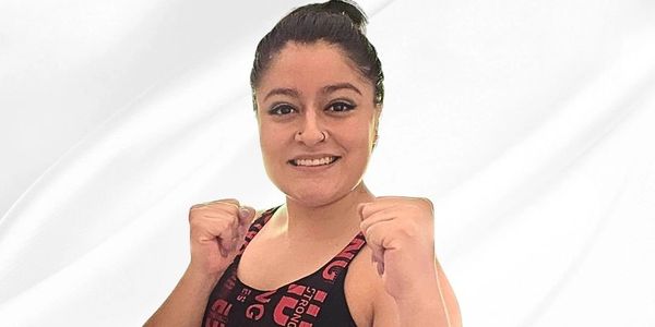 Woman in athletic wear posing with fists up for a workout.