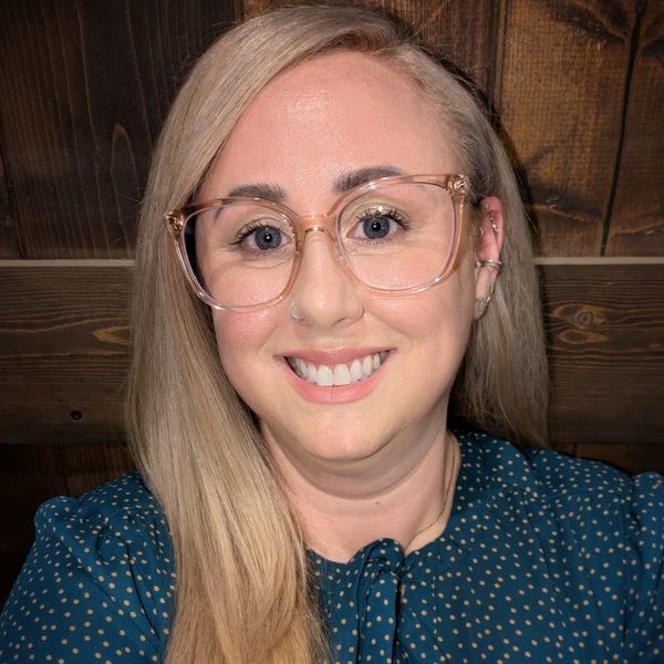 Smiling woman with glasses and blonde hair.