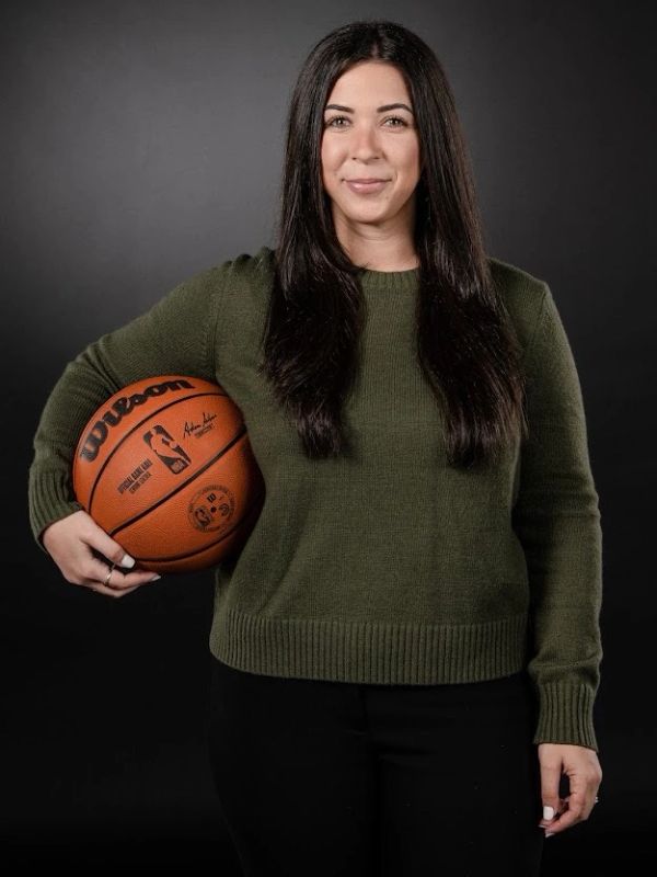 Woman holding a basketball and smiling.