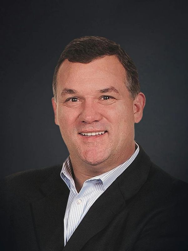 Smiling man in a black blazer and striped shirt.