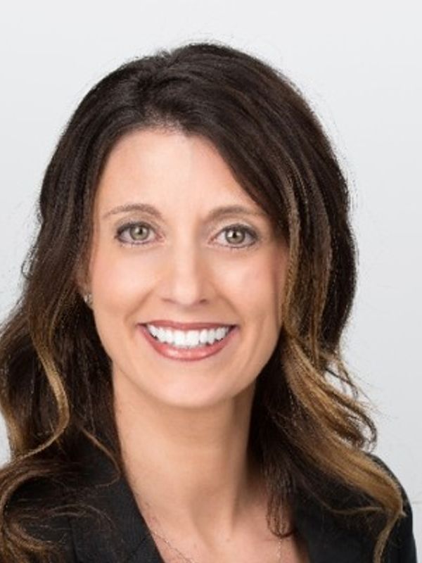 Smiling woman with long brown hair and a black blazer.
