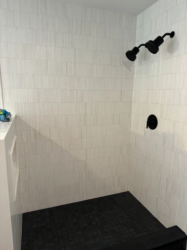Modern shower with black fixtures and tiled walls.