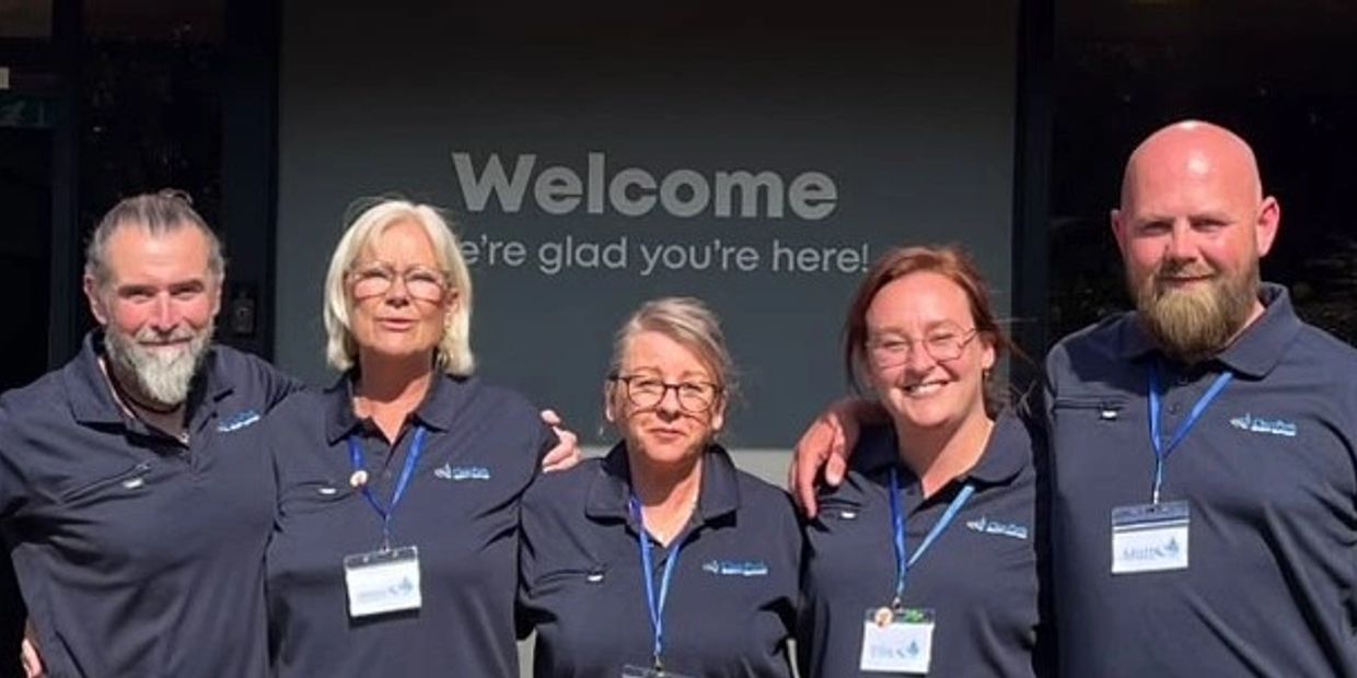 Group of five people smiling in uniform.