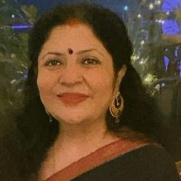 A woman smiling, wearing traditional attire and earrings.