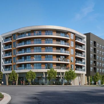 Modern multi-story apartment building with balconies and trees in front.