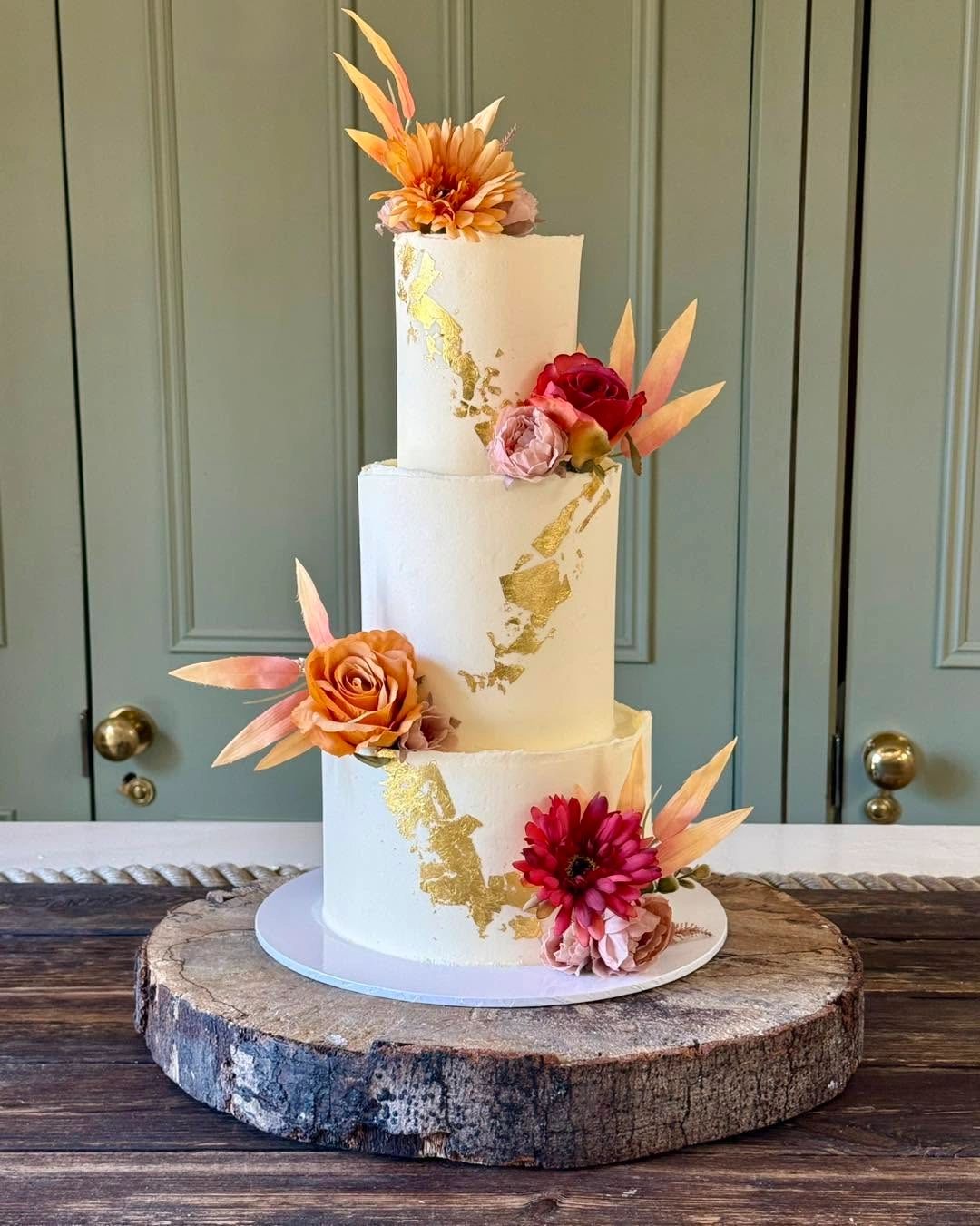 Elegant three-tier cake with gold accents and floral decorations.