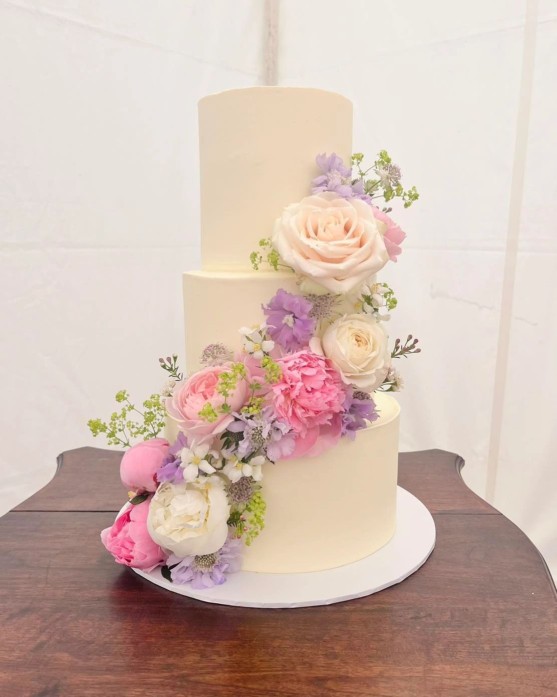 Elegant three-tier white cake with pastel floral decoration.